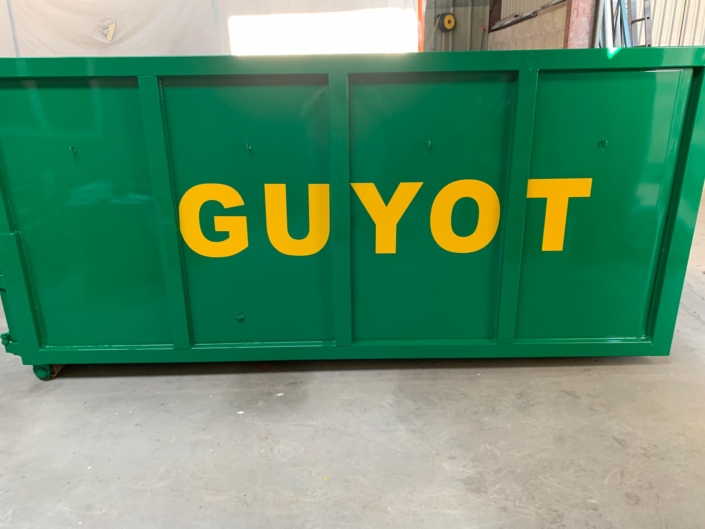 Photo d'une peinture de benne après travaux. Benne verte et mot clé "Guyot" peint en jaune.