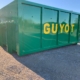Photo d'une peinture de benne après travaux. Benne verte et mot clé "Guyot" peint en jaune.